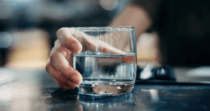 A hand holds a glass of water